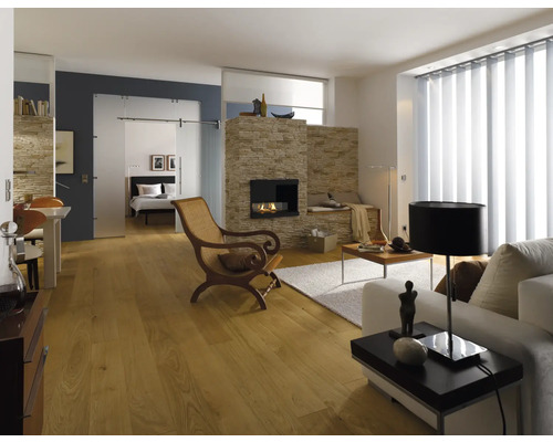 Heller Wohnraum mit Kamin, Holzfußboden, Couch, Sessel und Schiebetür zum Schlafzimmer