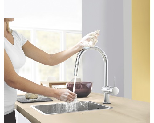 Frau wäscht sich die Hände an einem Spültisch mit einer Einhebelmischbatterie in einer Küche.