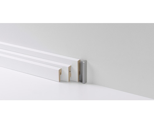 Verschiedene weiße und eine silberne Fußleiste vor einer Wand