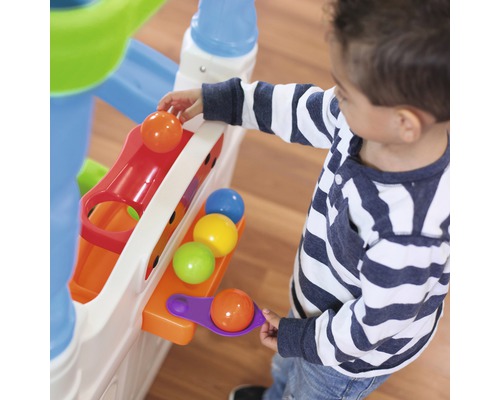 Ein Kind spielt mit einer Kugelbahn mit bunten Bällen.