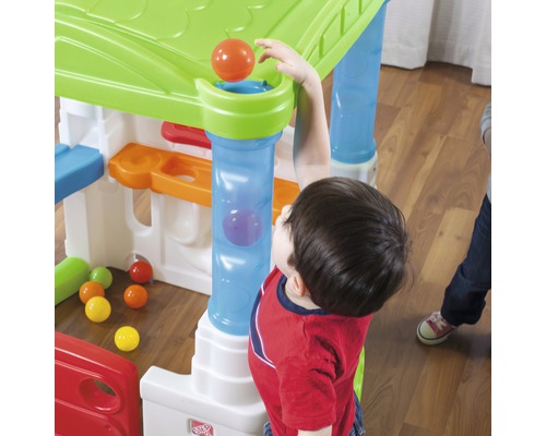 Kind spielt mit einem bunten Spielhaus mit Bällen und Rampen.