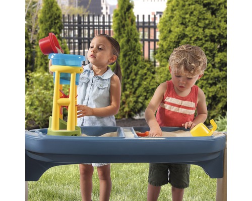 Kinder spielen mit einem Sand- und Wassertisch im Garten.