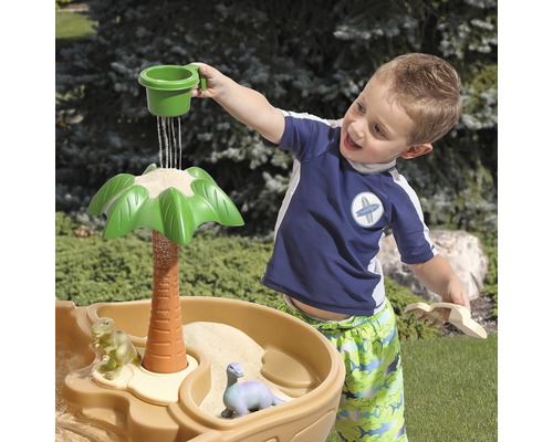 Kind spielt mit Sand- und Wassertisch mit Dinosaurier-Motiv im Freien