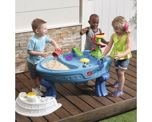 Kinder spielen mit einem Step2 Sand- und Wassertisch im Freien.