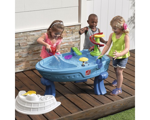 Kinder spielen mit einem blauen Step2 Wasserspieltisch im Freien.