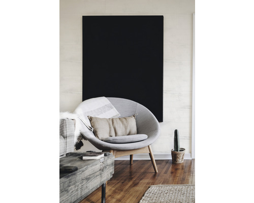 Wohnzimmer mit Sessel, Kissen und schwarzem Bild