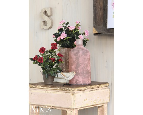 Dekorative Szene mit Kunstblumen, Vogel und Vase auf einem Tisch