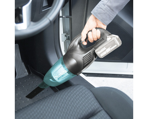 Person saugt mit einem Makita Akku-Handsauger den Fußraum eines Autos.