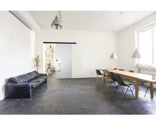 Heller Raum mit Sofa, Tisch, Stühlen und Glasschiebetür