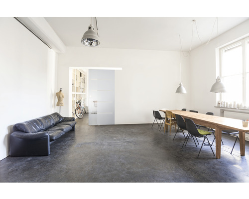 Innenaufnahme eines hellen Raumes mit Sofa, Esstisch und Schiebetür