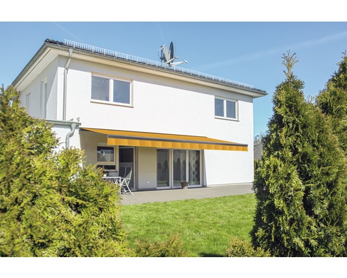 Hausfassade mit gelber Gelenkarmmarkise über der Terrasse