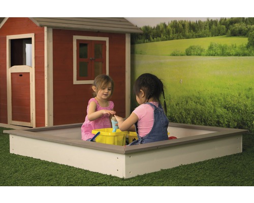 Zwei Kinder spielen in einem Sandkasten vor einem Spielhaus und einer Landschaftstapete.