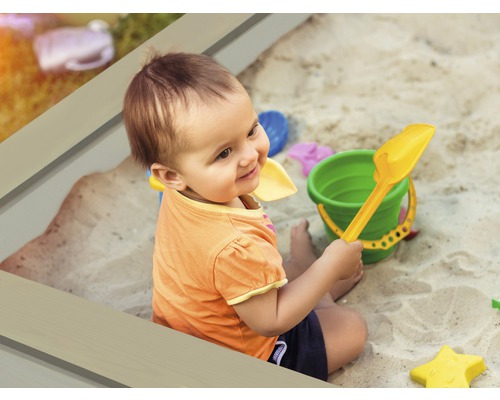 Kind spielt mit Sandkastenspielzeug im Sandkasten