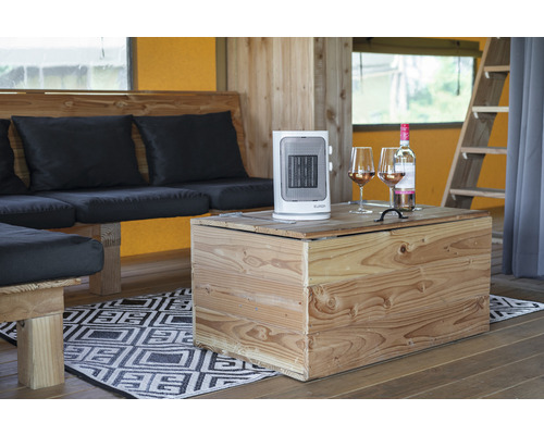 Interieuransicht mit Heizlüfter, Weinflasche und Weingläsern auf einem Holztisch neben einer Sitzecke