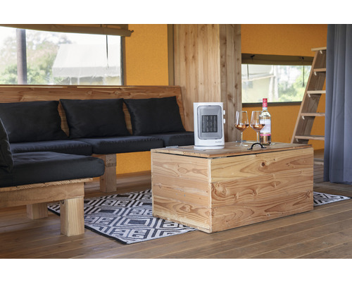 Innenraum eines Zeltes mit Holzmöbeln, einem Heizlüfter und einer Weinflasche mit Gläsern