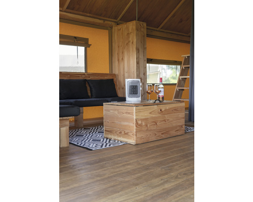 Innenraum eines Zeltes mit Holzmöbeln, Heizgerät und Getränken.