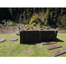 Hochbeet aus Holz im Garten mit Bepflanzung, Gießkanne und Gartengeräten