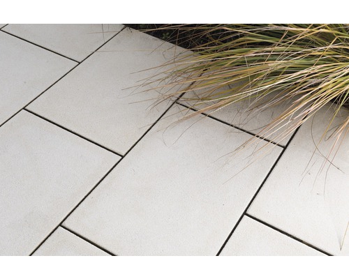 Verlegte Terrassenplatten aus Stein mit Grasbewuchs