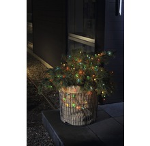 Dekorativer Weihnachtsbaum mit Lichtern in einem Jutesack und Drahtkorb im Außenbereich.