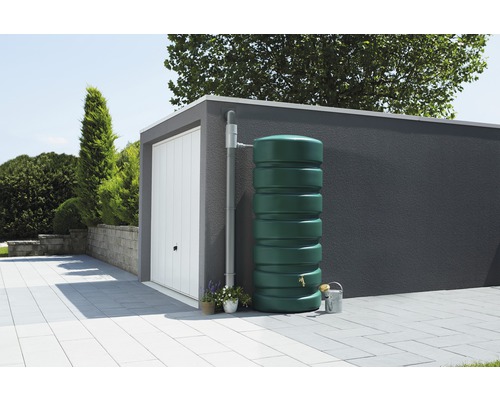 Regenspeicher im Garten neben einer Garage mit Regenfallrohr.