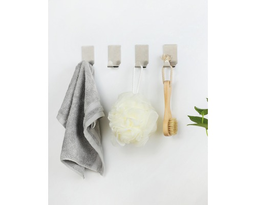 Vier Wandhaken mit Handtuch, Badeschwamm und Bürste an einer Wand