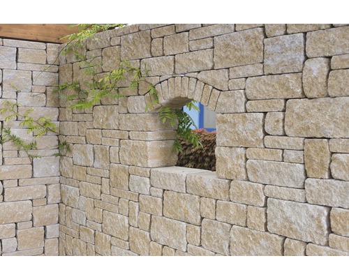Natursteinmauer mit Bogenfenster und Pflanzen
