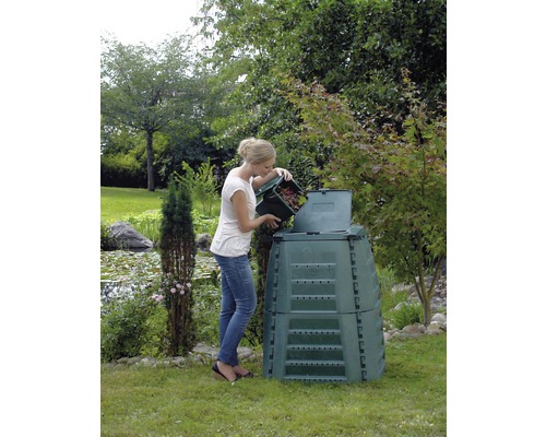 Frau befüllt Komposter mit Gartenabfällen im Garten.