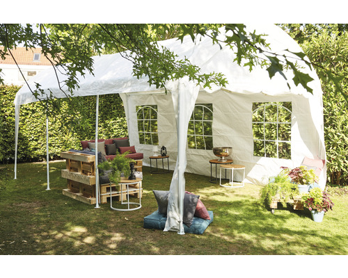 Gartenszene mit Partyzelt, Palettenmöbeln und Dekoration auf einer Rasenfläche.