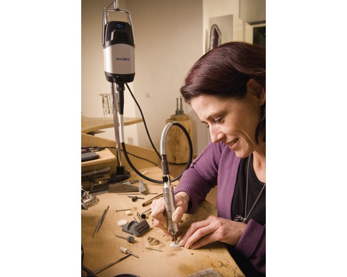 Frau arbeitet mit Dremel Multifunktionswerkzeug an einem Tisch