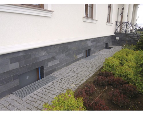 Außenansicht eines Hauses mit Natursteinfassade und gepflastertem Weg