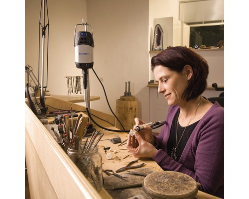 Frau arbeitet mit einem Dremel Multifunktionswerkzeug an einem Werkstück auf einem Werktisch