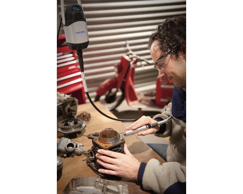 Mann verwendet Dremel Multifunktionswerkzeug an einem Motorblock auf einer Werkbank