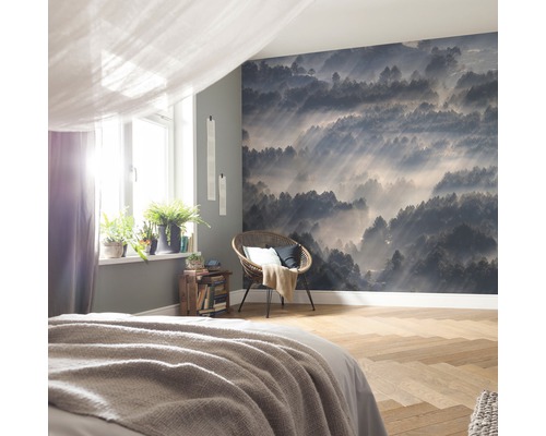 Schlafzimmer mit Fototapete eines nebligen Waldes, Sessel und Pflanzen auf dem Fensterbrett