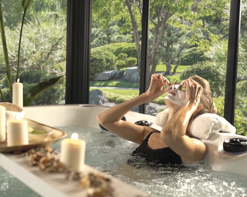 Frau entspannt im Whirlpool mit Blick auf einen Garten