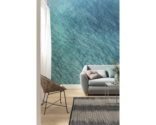 Wohnzimmer mit Fototapete mit Meeresmotiv, Sofa, Sessel und Teppich