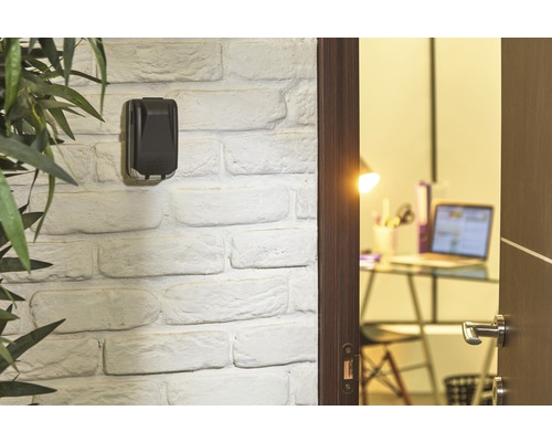 Schlüsselsafe an einer weißen Ziegelwand neben einer offenen Tür zu einem Büro.