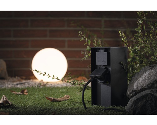 Gartensteckdose im Außenbereich mit Stromkabel und Leuchtkugel