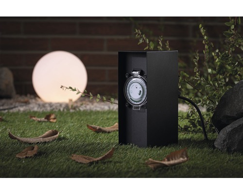 Zeitschaltuhr für den Außenbereich neben einer Kugelleuchte im Garten.