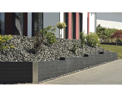Gestaltete Gartenszene mit Stützmauer, Steinen und Pflanzen vor einem Haus