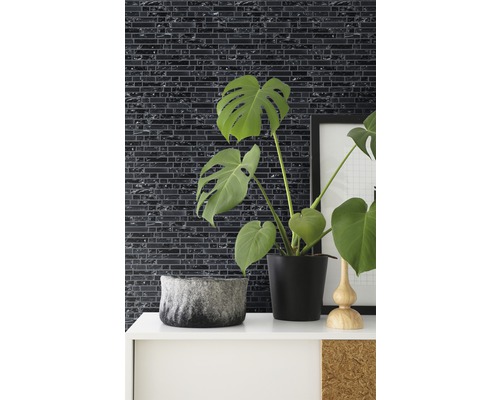 Dekorative Wandgestaltung mit Mosaikfliesen in einem Raum mit Zimmerpflanzen und Dekorationselementen.