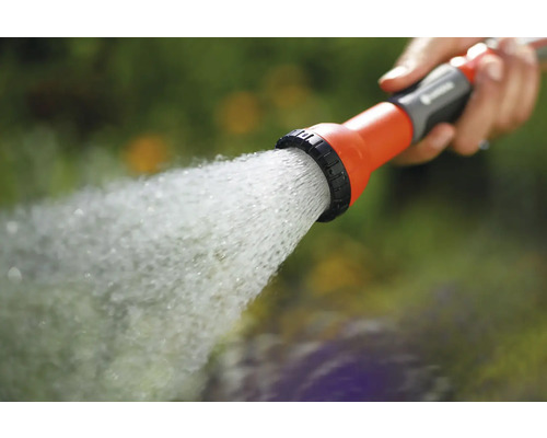 Eine Hand hält eine Gartenspritze, aus der Wasser austritt.