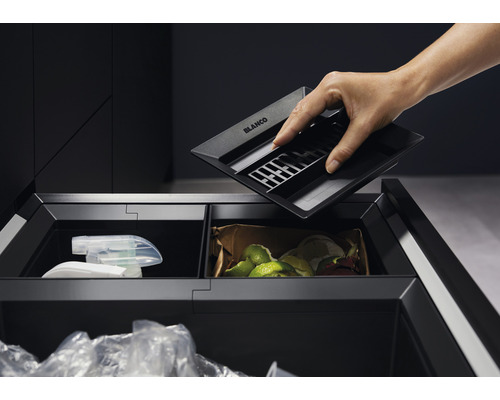 Person setzt Küchenabfallbehälter von Blanco in einen Auszugschrank mit Mülltrennsystem