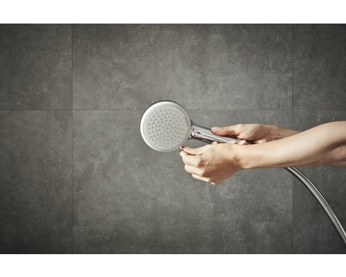 Handbrause mit Brauseschlauch vor gefliester Wand