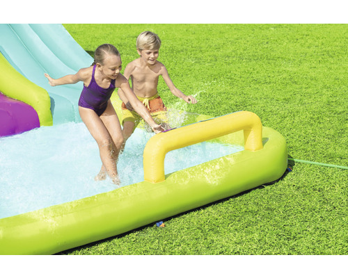 Aufblasbare Wasserrutsche mit spielenden Kindern im Garten.