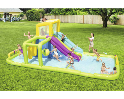 Aufblasbarer Wasserpark mit Rutsche und Pool im Garten mit spielenden Kindern