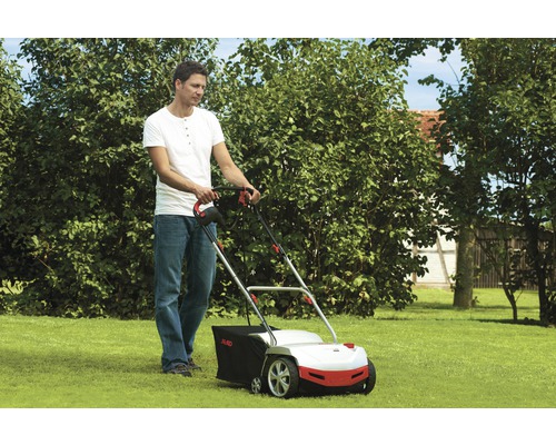 Ein Mann benutzt einen Rasenlüfter im Garten.