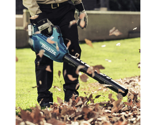 Ein Mann benutzt einen Makita Laubbläser im Garten, um Laub zu entfernen.