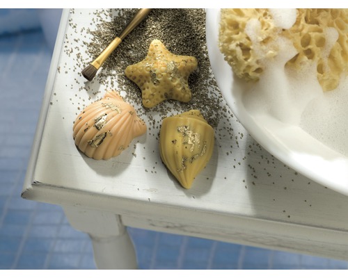 Dekorative Seifenstücke in Form von Meerestieren liegen mit einem Pinsel und einem Badeschwamm auf einem Tisch.