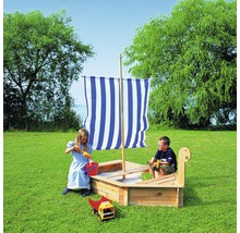 Sandkasten in Bootsform mit Kindern auf einer Wiese