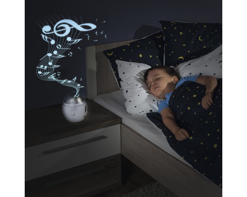 Kind schläft in einem Bett mit Spieluhrprojektion an der Wand.